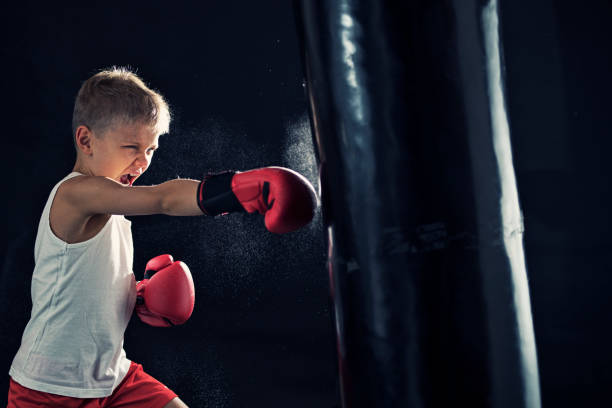 Little boy training boxing. The boy aged 8 is hitting hard the punching bag.